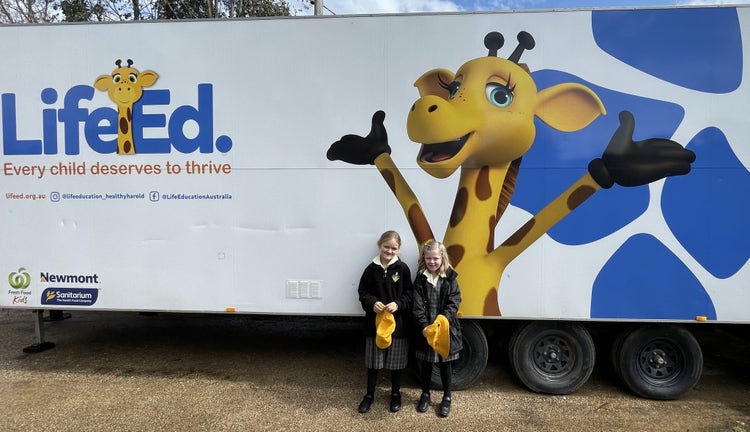 Two students in front of a Life Education van